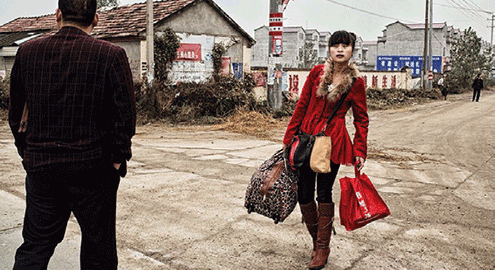 “A young woman waits for the bus at an intersection on the main road in Dongling, Anhui Province, which is among the largest exporters of migrant labour in China.”