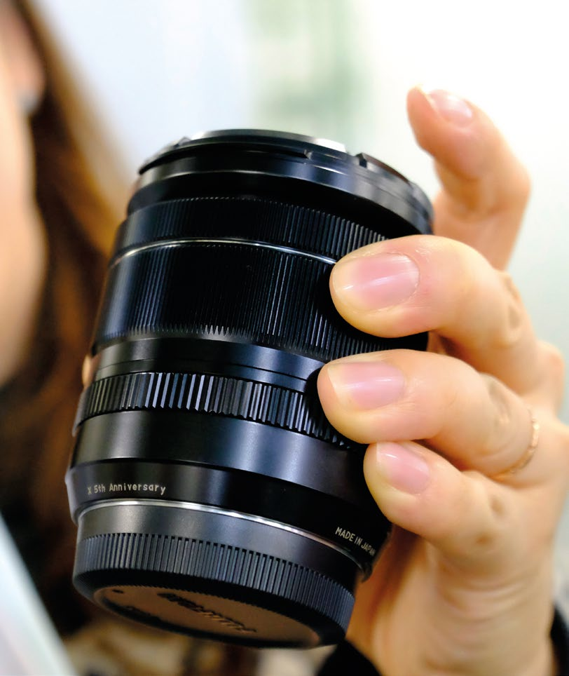 A Fujifilm employee holds a special, not for sale, Fujinon lens with the words “5th anniversary” engraved.